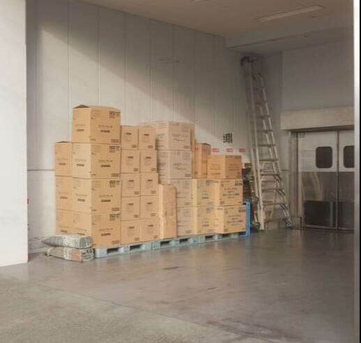 Card board boxes stacked on top of each other by a facility entrance 